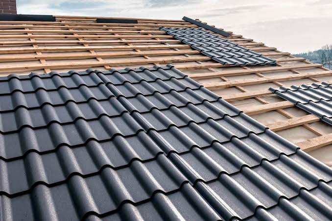Pose de tuiles anthracite sur des liteaux en bois.